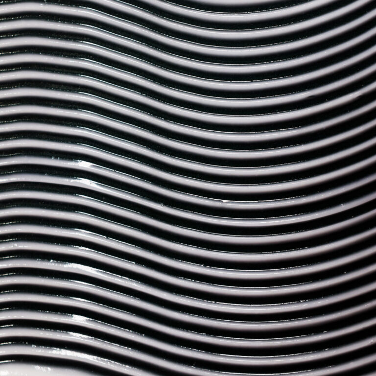 An abstract close-up view of parallel shiny silver lines creating a wavelike texture and pattern.