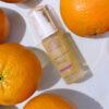 Sentence with Product Name: 20% vitamin C serum surrounded by fresh oranges, suggesting citrus-based skin nourishment.
