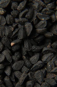 A close-up view of black seeds, possibly nigella sativa (black cumin), with a textured surface.