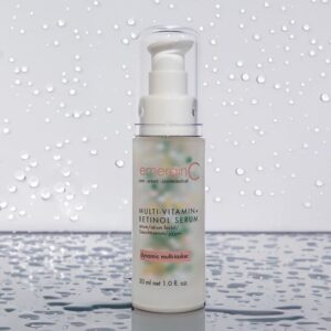 A bottle of emerginc multi-vitamin + retinol serum against a backdrop with water droplets.