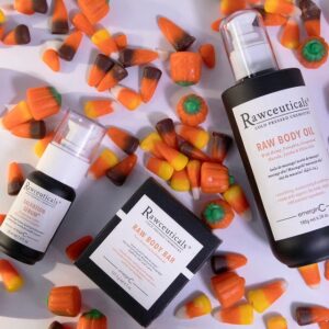 A collection of rawceuticals skincare products arranged amidst colorful candy corn.