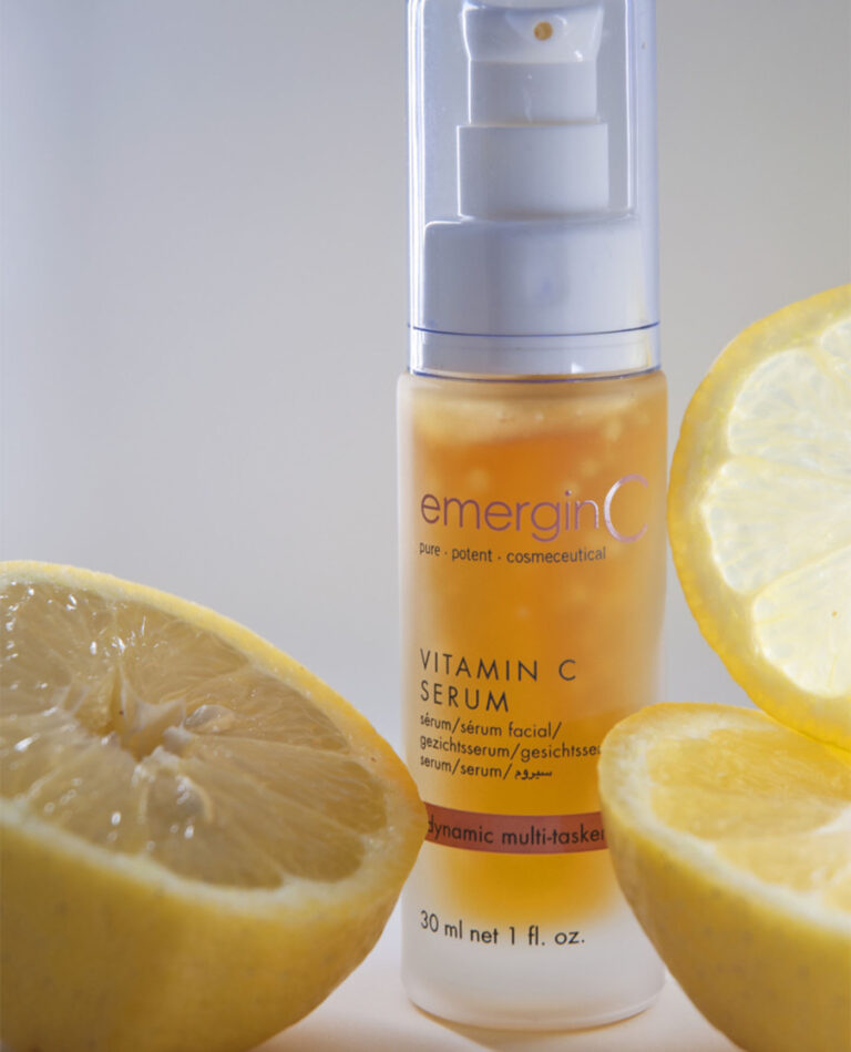 A bottle of emerginc vitamin c serum surrounded by fresh lemon slices, highlighting the citrus ingredient in the skincare product.