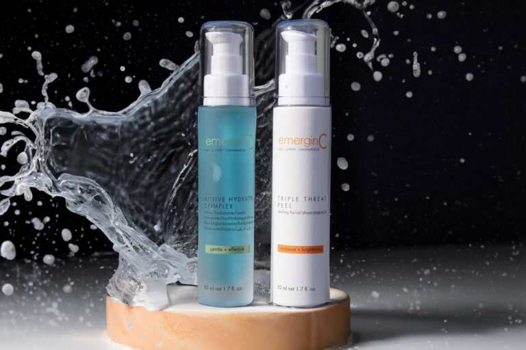 Two skincare products from emerginc, an active hydrating complex and a triple threat peel, presented on a pedestal with a dynamic splash of water in the background, highlighting their refreshing and hydrating qualities.