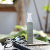 A bottle of Glow Guard™ placed on top of a journal, accompanied by a stylish pair of glasses, with a tranquil home office decor featuring green plants in the background.