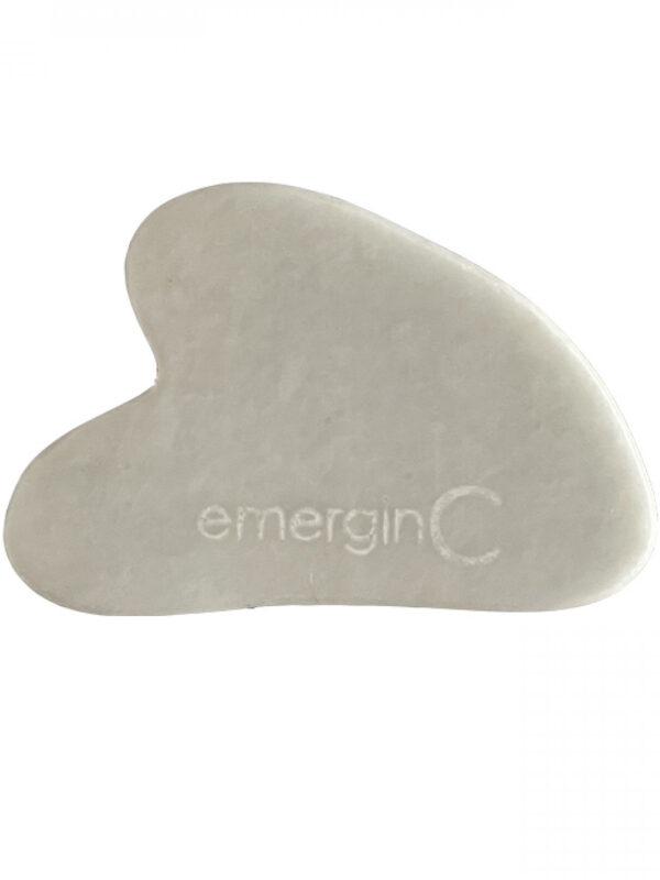 White heart-shaped Gua Sha with "emerginc" branding engraved on it.