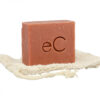 A Signature Facial Bar with the imprint "ec" resting on a natural fiber exfoliating pad, set against a white background.