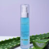 A sleek bottle of emerginc active hydrating complex skincare product positioned in front of fresh aloe vera leaves on a soft purple background, symbolizing gentle and effective hydration care.