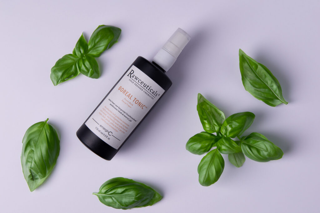 BOREAL TONIC™ surrounded by fresh green basil leaves on a clean, white background.