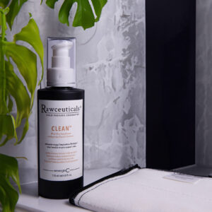Elegant and minimalist bathroom corner featuring CLEAN™ with a backdrop of stylish grey marble and a touch of greenery from a tropical plant.