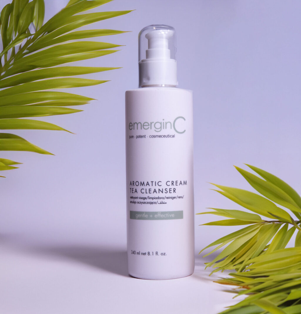 A bottle of emerginc Green Tea Cleanser with green leaves in the background, presented against a soft blue backdrop.