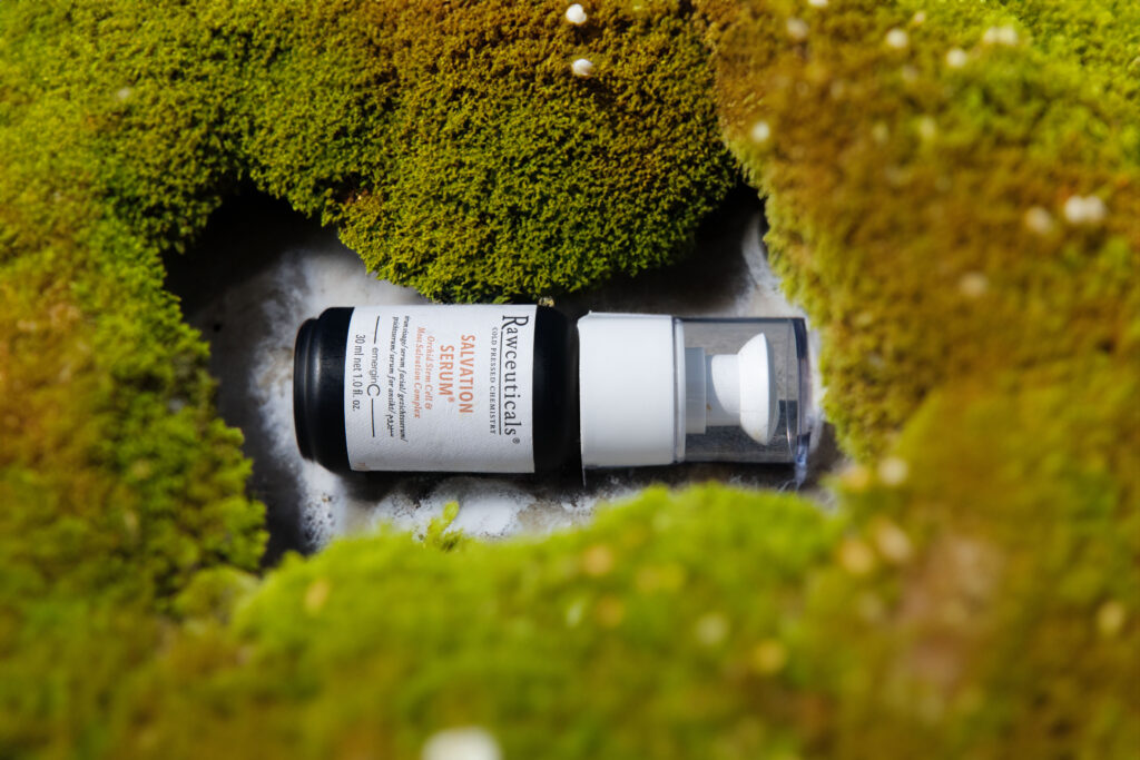 A prescription SALVATION SERUM® bottle nestled in a bed of lush green moss, creating a striking contrast between man-made pharmaceuticals and the natural environment.