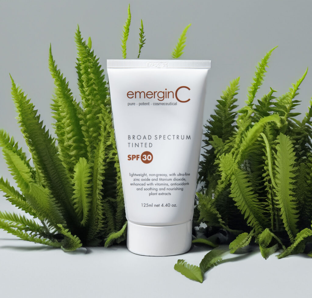 A tube of sun spf 30+ tinted amidst verdant fern leaves, suggesting a natural and protective skincare theme.