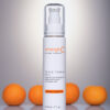 Bottle of emerginc triple threat peel skincare product, with a focus on radiance and brightening, elegantly presented with oranges to hint at its citrus ingredients, against a soft gradient background.