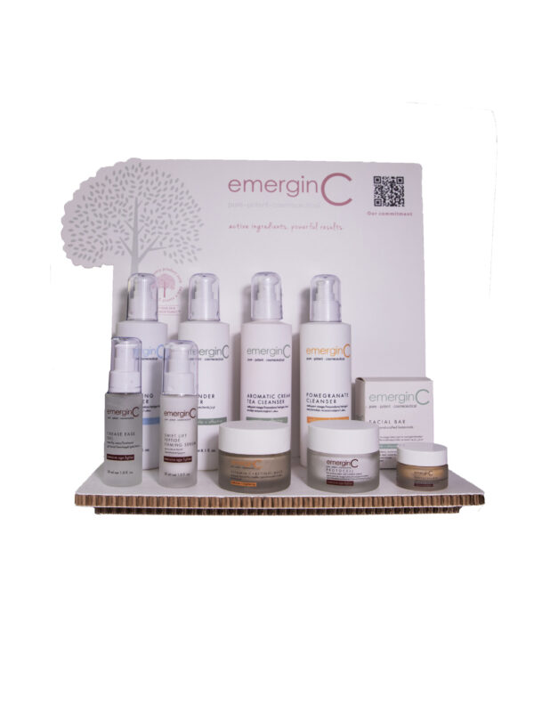 A display of emerginc signature laser cut displays, featuring various creams and serums, arranged on a branded countertop stand.