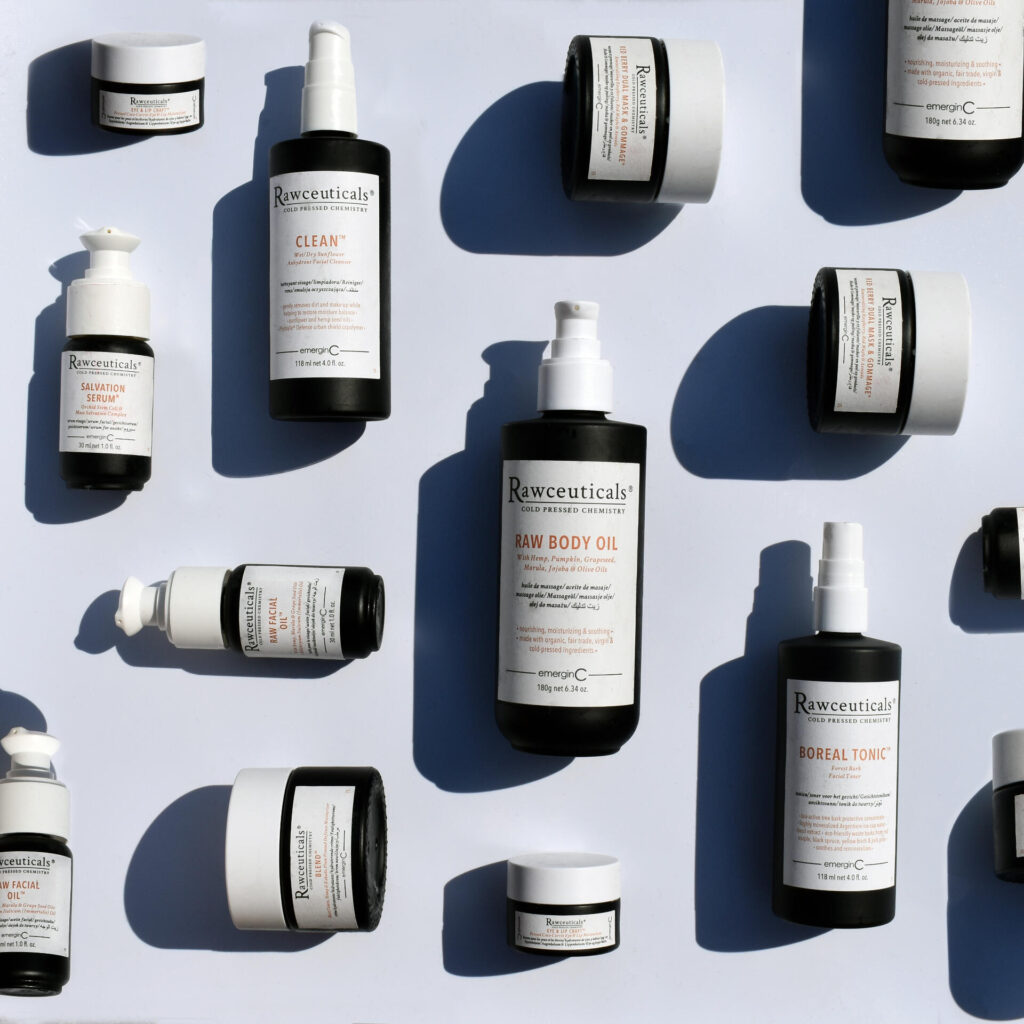 Assorted Rawceuticals collection skincare products, including bottles and jars, are arranged on a flat white surface with soft shadows.