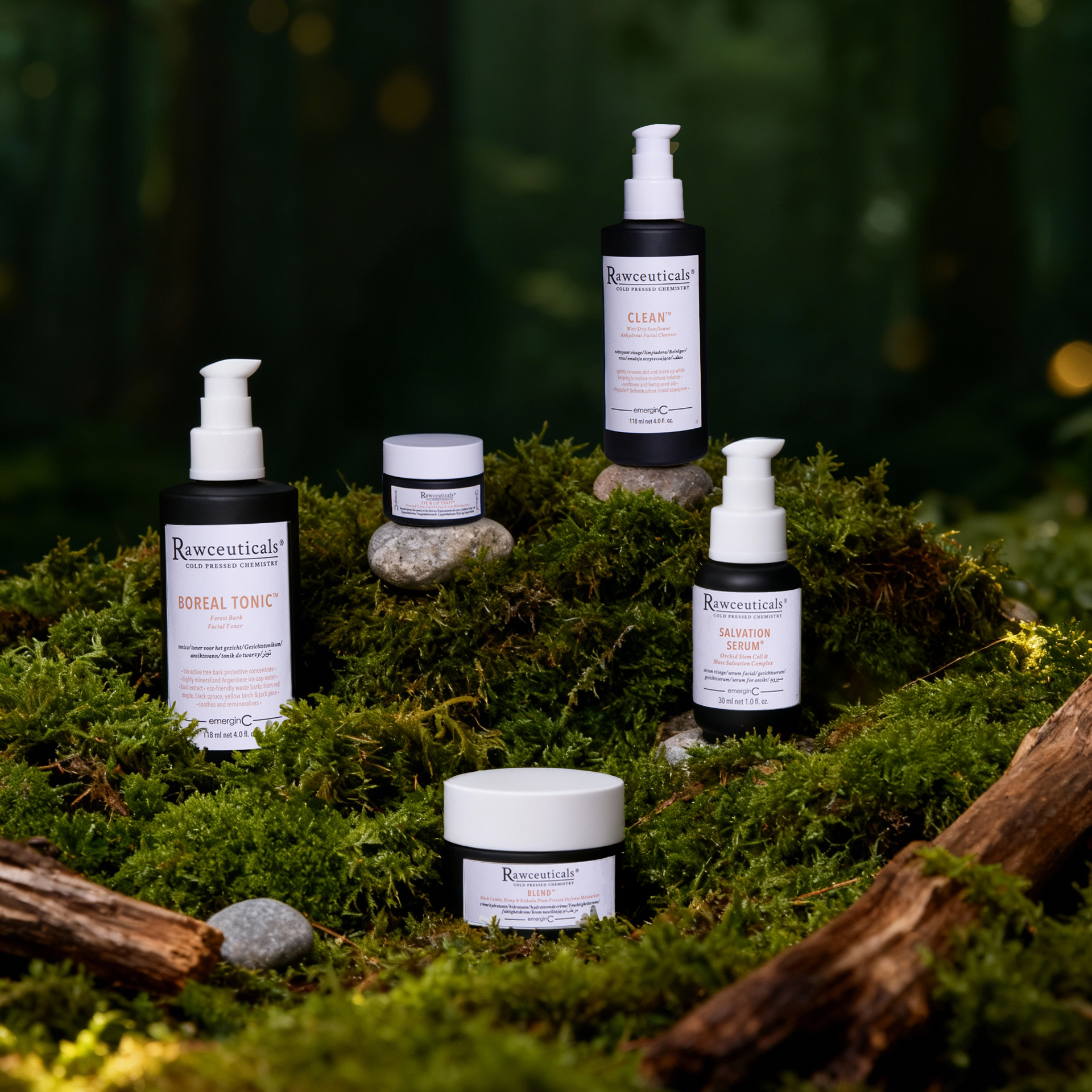 Five Rawceuticals Collection skincare products are arranged on moss and stones in a forest setting, surrounded by logs and greenery. The natural, earthy scene highlights the Rawceuticals Collection’s connection to nature.