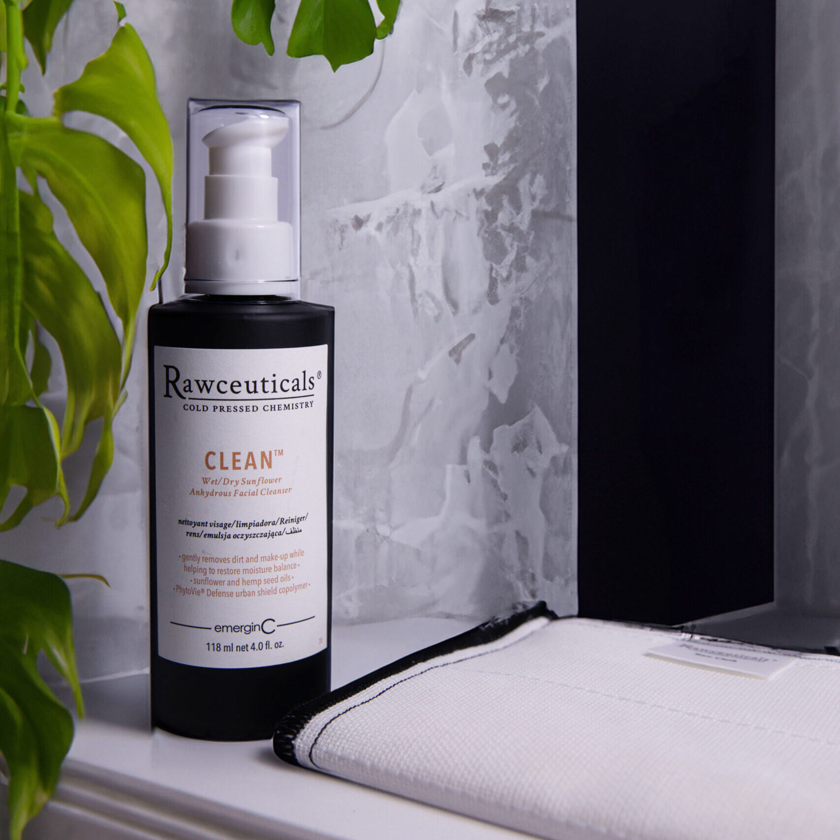 Elegant and minimalist bathroom corner featuring CLEAN™ with a backdrop of stylish grey marble and a touch of greenery from a tropical plant.
