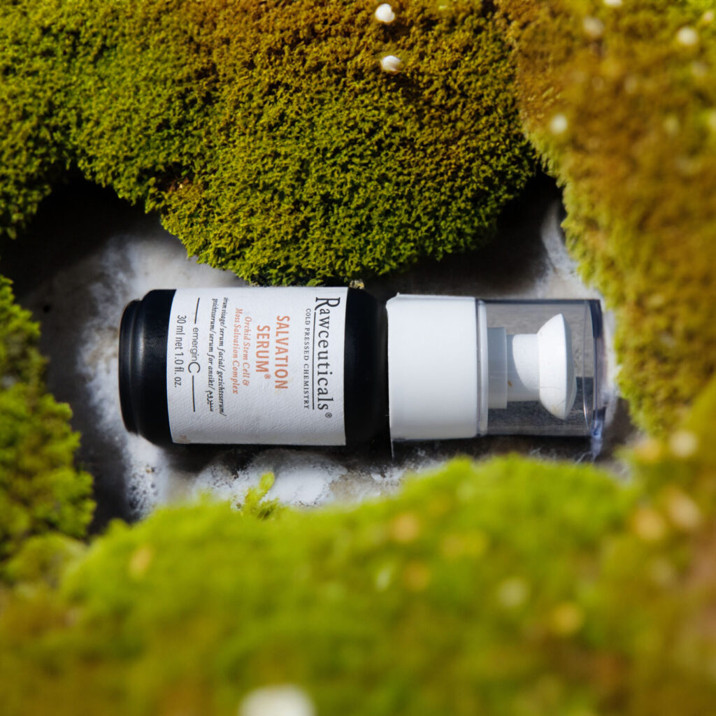 A prescription SALVATION SERUM® bottle nestled in a bed of lush green moss, creating a striking contrast between man-made pharmaceuticals and the natural environment.